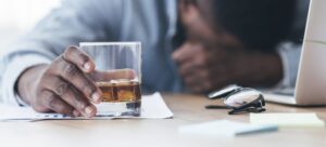 person with head down holding a glass of beer